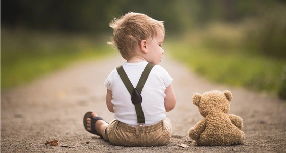 Young child sitting with a teddy bear, representing speech therapy support for children